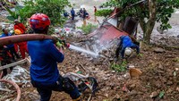 Tim SAR menggunakan selang air bertekanan melakukan evakuasi untuk mencari korban yang tertimbun tanah longsor di Empang, Bogor, Rabu (15/3/2023). (Aditya Aji/AFP/Getty Images)  
