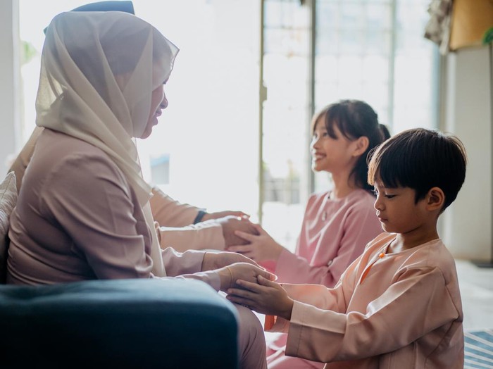 Malay Muslim children in traditional clothings asking forgiveness to their parents during Hari Raya Aidilfitri celebration