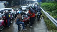 Para pemotor bergotong-royong menurunkan kendaraan dari trotoar Jalan Inspeksi Kalimalang, Kota Bekasi.