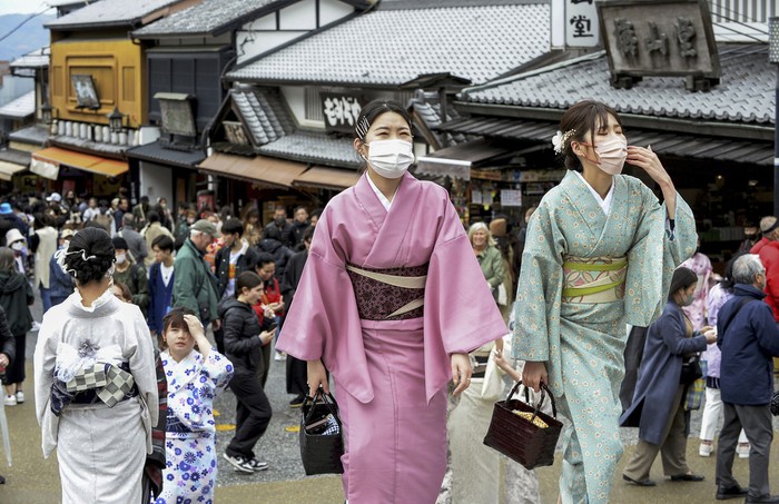 Visitors walk along a sightseeing destination in Kyoto, western Japan Monday, March 13, 2023. Japan on Monday dropped its request for people to wear masks after three years, but hardly anything changed in the country that has had an extremely high regard for their effectiveness at anti-virus protection. (Kyodo News via AP)