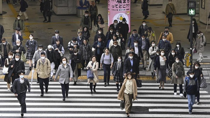 Potret Warga Jepang Tetap Pakai Masker Meski Aturan Dilonggarkan People walk across an intersection in Osaka, western Japan, Monday, March 13, 2023. Japan is dropping its mask wearing request beginning Monday for the first time in three years as the country further eases COVID-19 rules in public places and tries to expand business and other activity. (Yu Nakajima/Kyodo News via AP)
