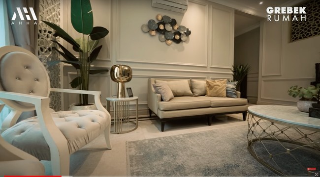 Bergaya klasik modern, begini penampakan ruang tamu di rumah Arie dan fenita. Ruang tamu tersebut tampak nyaman dan juga estetik dengan beberapa pajangan, hiasan dinding, dan tanaman hijau di sudut ruangan. Foto: YouTube/AH