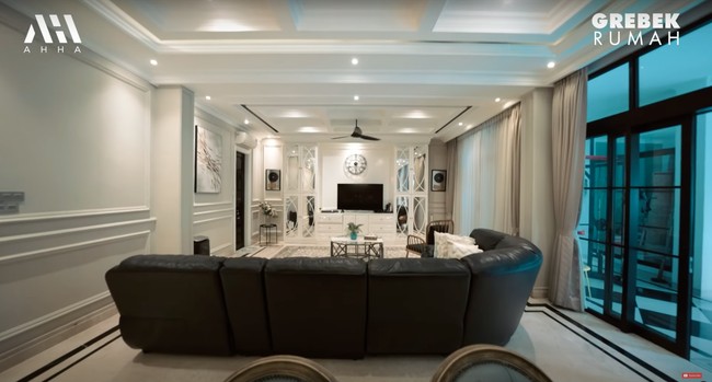 Masuk ke bagian lebih dalam rumah terdapat ruang keluarga yang didominasi warna hitam dan putih. Ruang keluarga di rumah Arie dan Fenita itu dilengkapi dengan sofa hitam panjang dan sebuah televisi. Foto: YouTube/AH