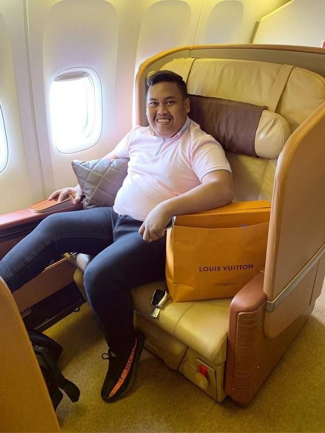 Muhammad Akbar selalu mengabadikan momennya duduk di kelas bisnis saat traveling dengan pesawat. Tidak lupa memamerkan belanjaan dari butik luxury brand kenamaan dunia. Tampak di foto ini, ia memakai sneakers Yeezy yang harganya bisa menyentuh Rp 5 juta. (Foto: Instagram/@ajudan_pribadi)