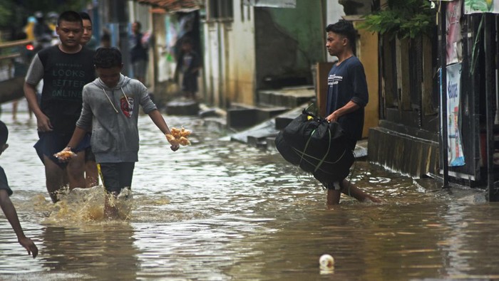 Sejumlah warga melewati jalan terendam banjir di Cibeber, Cilegon, Banten, Rabu (15/3/2023). Banjir tersebut akibat tingginya curah hujan sejak Selasa (14/3) sore sehingga sungai di dekat kampung tersebut meluap ke area pemukiman. ANTARA FOTO/Asep Fathulrahman/nym.