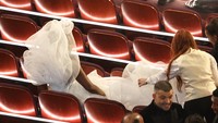 Dress panjang itu cukup membuat repot beberapa kru sehingga ia pun harus duduk lebih dulu sebelum tamu-tamu lainnya. Los Angeles Times via Getty Imag/Myung J. Chun