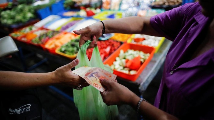 A vegetable seller weights carrots at a greengrocery store in a local market, as Argentinas annual inflation rate tore past 100% in February, the countrys statistics agency said on Tuesday, the first time it has hit triple figures since a period of hyperinflation in 1991, over three decades ago, in Buenos Aires, Argentina March 14, 2023. REUTERS/Agustin Marcarian