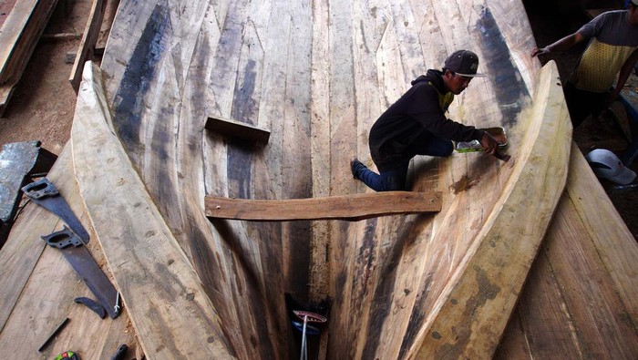 Melihat Proses Pembuatan Perahu Nelayan Pekerja menyelesaikan pembuatan kapal nelayan tradisional di Tambakrejo, Sumbermanjing Wetan, Malang, Jawa Timur, Rabu (15/3/2023). Pembuatan kapal nelayan berkapasitas 40 ton yang biasanya dikerjakan selama tiga bulan dengan biaya sekitar RP600 juta itu kini menghabiskan waktu enam bulan dengan biaya Rp800 juta per kapal yang disebabkan sulitnya mendapatkan bahan baku berupa kayu jati berkualitas. ANTARA FOTO/Irfan Sumanjaya/Zk/rwa.