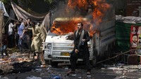 Pendukung mantan Perdana Menteri Imran Khan melemparkan batu ke arah polisi di sebelah kendaraan yang terbakar saat bentrokan.  