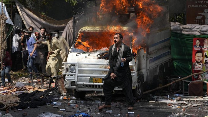 Supporters of former Prime Minister Imran Khan chant anti government slogans as they gather outside Khans residence, in Lahore, Pakistan, Wednesday, March 15, 2023. Pakistani police have paused efforts to arrest former Prime Minister Imran Khan on graft charges after clashes continued for a second day outside his home in the eastern city of Lahore. (AP Photo/K.M. Chaudary)