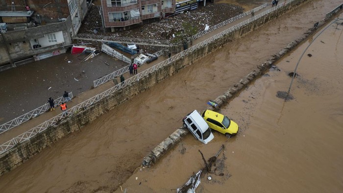 People leave during floods after heavy rains in Sanliurfa, Turkey, Wednesday, March 15, 2023. Floods caused by torrential rains hit two provinces that were devastated by last month's earthquake, killing at least 10 people and increasing the misery for thousands who were left homeless, officials and media reports said Wednesday. At least five other people were reported missing. (Hakan Akgun/DIA via AP)
