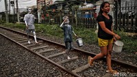 Tampak beberapa manusia silver melintas di jalur rel kereta api Jakarta Kota.