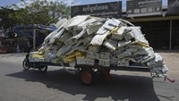 Pengendara motor menarik gerobak berisi potongan karet di jalan utama Phnom Penh, Kamboja, Kamis (16/3/2023).