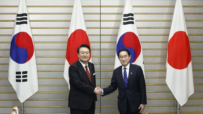 South Koreas President Yoon Suk Yeol (L) and Japans Prime Minister Fumio Kishida shake hands ahead of a summit meeting at the prime ministers official residence in Tokyo on 16 March 2023. (Photo by Kiyoshi Ota / POOL / AFP)