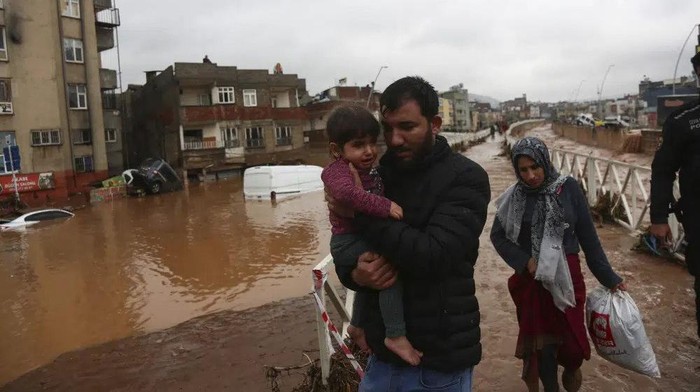 People leave during floods after heavy rains in Sanliurfa, Turkey, Wednesday, March 15, 2023. Floods caused by torrential rains hit two provinces that were devastated by last months earthquake, killing at least 10 people and increasing the misery for thousands who were left homeless, officials and media reports said Wednesday. At least five other people were reported missing. (Hakan Akgun/DIA via AP)