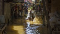Warga berjalan melintasi banjir di Barabai, Kabupaten Hulu Sungai Tengah, Kalimantan Selatan, Jumat (17/3/2023).