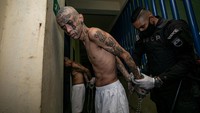 Foto-foto ini memperlihatkan kelompok pertama dari para narapidana - sebagian besar bertato, bertelanjang kaki, serta tangan dan kakinya diborgol - digiring ke ruangan utama penjara. (Press Secretary Of The Presidency Of El Salvador/REUTERS)