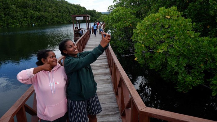 EKOWISATA MANGROVE DI TELUK YOUTEFA JAYAPURA Sejumlah pengunjung melintasi jembatan kayu di kawasan Ekowisata Mangrove Kampung Tobati, Distrik Jayapura Selatan, Kota Jayapura, Papua, Minggu (19/03/2023). Hutan mangrove yang berada di kawasan Teluk Youtefa dan memiliki luas sekitar 233,12 Ha tersebut dikelola oleh masyarakat dari Kampung Tobati selaku pemilik ulayat kawasan hutan bakau dengan tarif masuk Rp 10.000 per orang. ANTARA FOTO/Sakti Karuru/YU