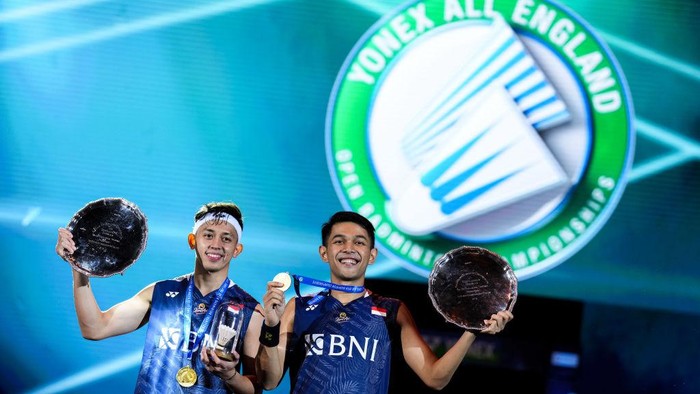 BIRMINGHAM, ENGLAND - MARCH 19: Fajar Alfian (R) and Muhammad Rian Ardianto of Indonesia pose with their trophies on the podium after the Mens Double Final match against Mohammad Ahsan and Hendra Setiawan of Indonesiaon on day six of the Yonex All England Badminton Championships at Utilita Arena Birmingham on March 19, 2023 in Birmingham, England. (Photo by Shi Tang/Getty Images)