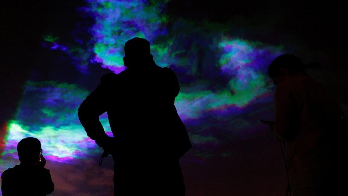 People stand next to the northern lights installation 