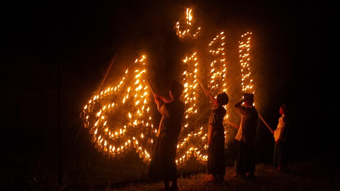 Sejumlah anak menyalakan karya instalasi sentir yang membentuk lafadz Allah di Triharjo, Sleman, D.I Yogyakarta, Minggu (19/3/2023). Penyalaan karya instalasi sentir oleh warga sekitar tersebut guna menyambut Ramadhan 1444 H. ANTARA FOTO/Andreas Fitri Atmoko/YU
