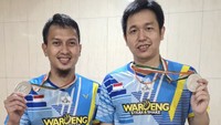 Berpose dengan medali kemenangan, Ahsan dan Hendra pamer senyum bangga. Keduanya juga mengenakan kaos sponsor dari restoran steak.