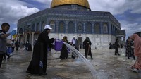 Relawan Palestina membersihkan tanah di luar Masjid Dome of Rock di kompleks Masjid Al-Aqsa di Kota Tua Yerusalem, Sabtu(18/3/2023).  
