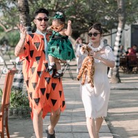 Siti Badriah dengan gaun putih dan kalaung mutiaranya cosplay menjadi karakter Wilma Flinstone, sementara sang suami mengenakan kostum ikonik berwarna oranye lengkap dengan dasi biru milik karakter suami Wilma, Fred Flinstone. Sama-sama mengenakan kaca mata hitam, ketiganya tampak begitu menawan. Foto: Instagram/@krisjianabah