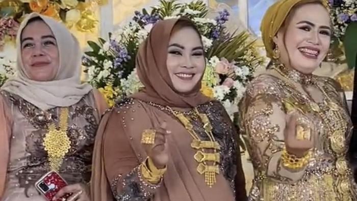 Emak-emak di Madura yang berpenampilan bak toko emas berjalan saat menghadiri kondangan. (Foto: Dok. TikTok @fuad_fahrozi.)