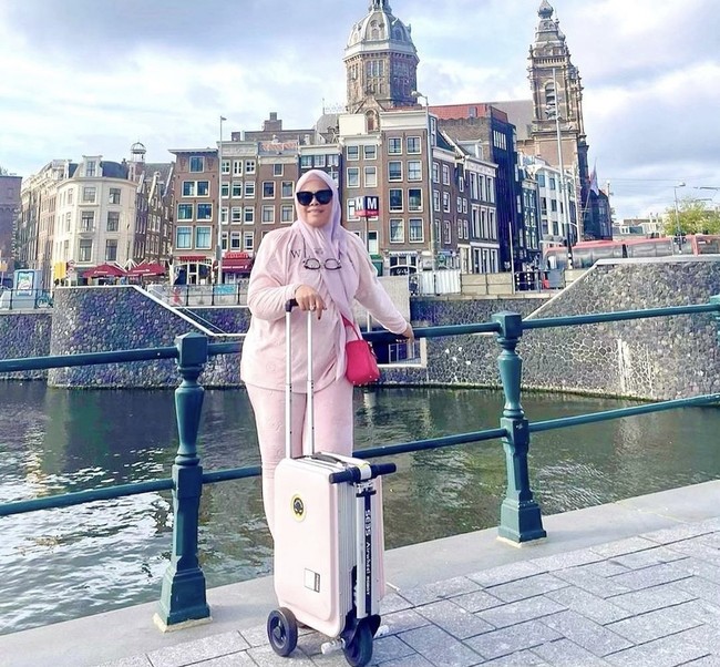 Tas Hermes juga menjadi pilihan istri Sekda Riau saat berpose liburan di luar negeri sambil menenteng koper. Adrias tampak memakai Hermes Lindy berwarna pink yang harganya lebih dari Rp 100 juta. Foto: Dok. Instagram, Twitter