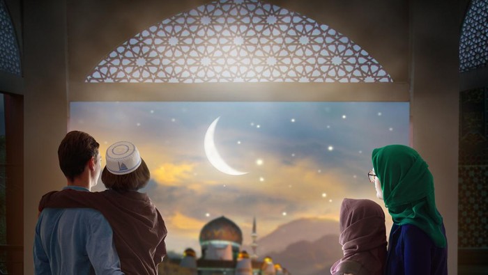 Ramadan Kareem greeting. Family at window looking at Islamic city with mosque skyline, crescent moon and stars. Muslim parents and children pray. Mother, father and kids celebrate end of fasting.