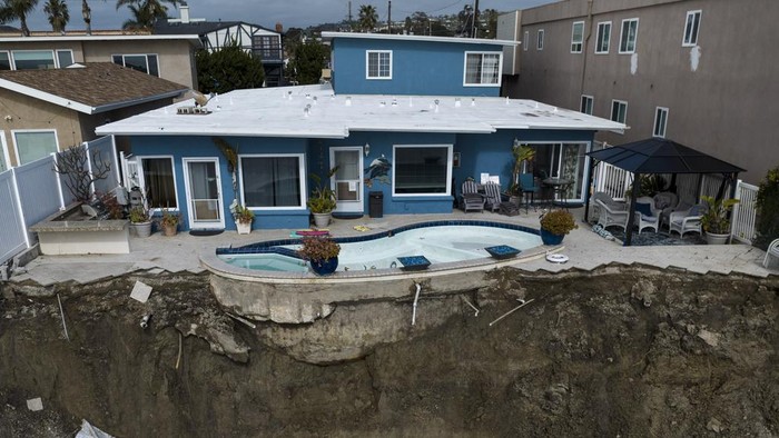 Penampakan Apartemen di California Roboh Akibat Longsor In this image taken with a drone, a residential swimming pool hangs on a cliffside after a landslide occurred in San Clemente, Calif., Thursday, March 16, 2023. (AP Photo/Jae C. Hong)