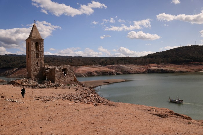 A couple walks on the cracked ground of the Baells reservoir as drinking water supplies have plunged to their lowest level since 1990 due to extreme drought in Catalonia, in the village of Cersc, in the region Bergueda, Spain March 14, 2023. REUTERS/Nacho Doce