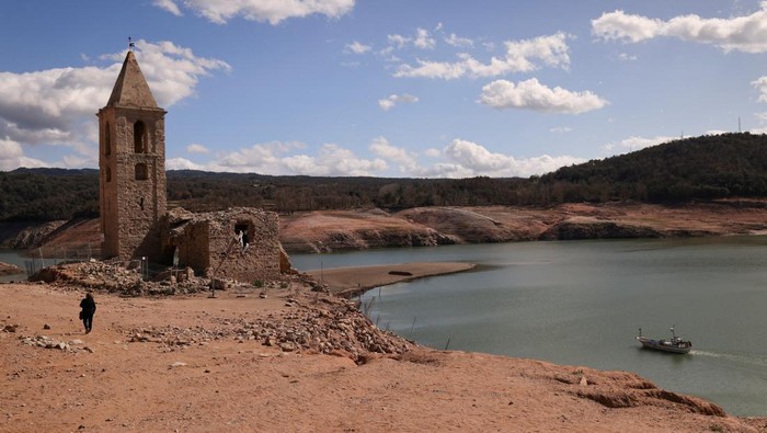 A couple walks on the cracked ground of the Baells reservoir as drinking water supplies have plunged to their lowest level since 1990 due to extreme drought in Catalonia, in the village of Cersc, in the region Bergueda, Spain March 14, 2023. REUTERS/Nacho Doce