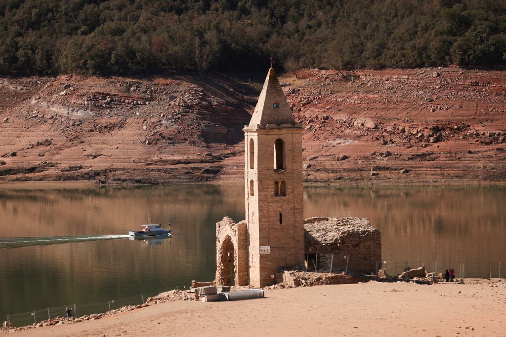 A couple walks on the cracked ground of the Baells reservoir as drinking water supplies have plunged to their lowest level since 1990 due to extreme drought in Catalonia, in the village of Cersc, in the region Bergueda, Spain March 14, 2023. REUTERS/Nacho Doce