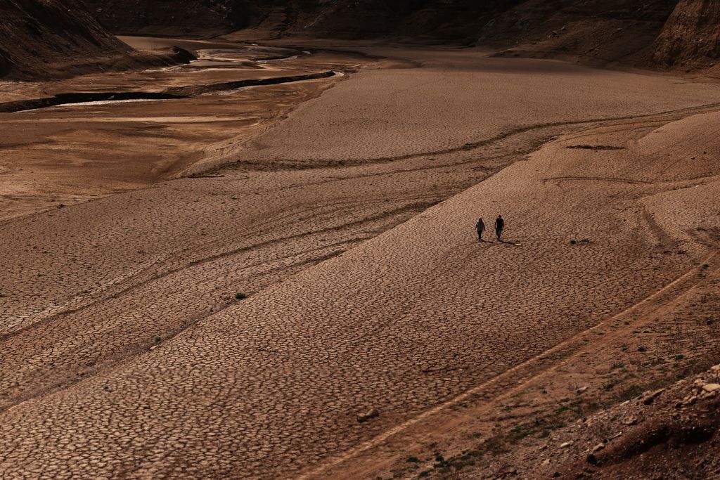 A couple walks on the cracked ground of the Baells reservoir as drinking water supplies have plunged to their lowest level since 1990 due to extreme drought in Catalonia, in the village of Cersc, in the region Bergueda, Spain March 14, 2023. REUTERS/Nacho Doce
