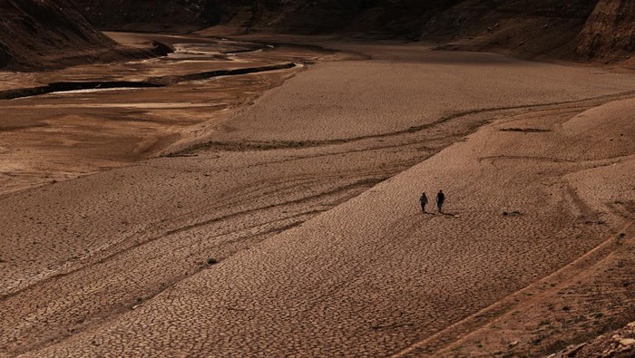 A couple walks on the cracked ground of the Baells reservoir as drinking water supplies have plunged to their lowest level since 1990 due to extreme drought in Catalonia, in the village of Cersc, in the region Bergueda, Spain March 14, 2023. REUTERS/Nacho Doce