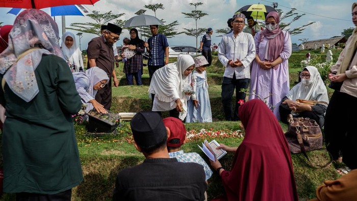 Indonesian Muslims readings from the Quran during make pilgrimages to their familys graves to pray ahead of the holy month of Ramadan at a cemetery for COVID-19 victims on March 19, 2023 in Medan, Indonesia.  Muslims from Indonesia are getting ready to welcome the holy month of Ramadan by cleaning themselves bathing in the river and cleaning family graves. Colorful street parades take place along with family rituals and a large-scale party ending with Eid al-Fitr celebrations. (Photo by Ivan Damanik/NurPhoto via Getty Images)