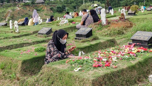 Indonesian Muslims readings from the Quran during make pilgrimages to their familys graves to pray ahead of the holy month of Ramadan at a cemetery for COVID-19 victims on March 19, 2023 in Medan, Indonesia.  Muslims from Indonesia are getting ready to welcome the holy month of Ramadan by cleaning themselves bathing in the river and cleaning family graves. Colorful street parades take place along with family rituals and a large-scale party ending with Eid al-Fitr celebrations. (Photo by Ivan Damanik/NurPhoto via Getty Images)