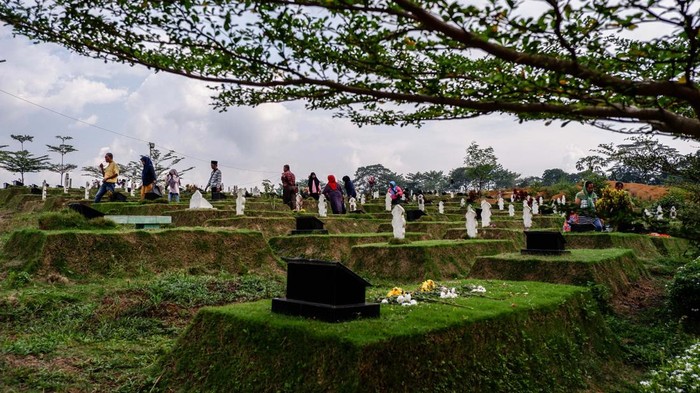 Indonesian Muslims readings from the Quran during make pilgrimages to their familys graves to pray ahead of the holy month of Ramadan at a cemetery for COVID-19 victims on March 19, 2023 in Medan, Indonesia.  Muslims from Indonesia are getting ready to welcome the holy month of Ramadan by cleaning themselves bathing in the river and cleaning family graves. Colorful street parades take place along with family rituals and a large-scale party ending with Eid al-Fitr celebrations. (Photo by Ivan Damanik/NurPhoto via Getty Images)