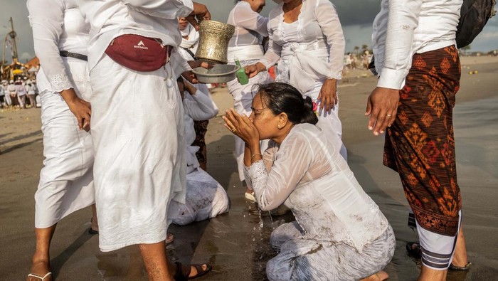 CANGGU, BALI, INDONESIA - MARCH 19:  Balinese Hindus woman in a state of trance, screams during Melasti Ritual prior to Nyepi Day on March 19, 2023 at Batubolong Beach, in Canggu Bali, Indonesia. After three years of performing purification ceremony ahead of Nyepi Day on a small scale due to the COVID-19 pandemic Balinese Hindus dressed in predominantly white attire carried sacred effigies of gods and goddesses and ritual paraphernalia from their village temples to the beach to perform a purification ceremony called the Melasti ritual. Balinese Hindus believe the Melasti ritual is a must perform ahead of Nyepi Day, The Day of Silence, to cleanse the soul and nature, recharge the supernatural power of the temples sacred objects and cleanse the temple paraphernalia. The Nyepi Day is a national holiday in Indonesia and is a day for self-reflection and abstaining from distractions such as entertainment. (Photo by Agung Parameswara/Getty Images)