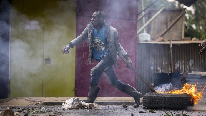 A protester pulls a burning barricade towards police in the Kibera slum of Nairobi, Kenya Monday, March 20, 2023. Hundreds of opposition supporters have taken to the streets of the Kenyan capital over the result of the last election and the rising cost of living, in protests organized by the opposition demanding that the president resigns from office. (AP Photo/Ben Curtis)