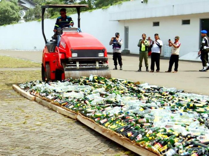 Polisi memusnahkan belasan ribu botol miras hasil razia di Karawang, Selasa (21/3/2023).