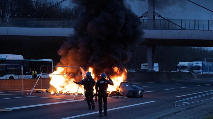 Prancis Memanas, Jalan Raya di Rennes Diblokir Police officers work near a burning barricade on a highway amid a protest against pension reform, in Rennes, France, March 20, 2023, in this image obtained from social media. Twitter @DHR_Damien/via REUTERS THIS IMAGE HAS BEEN SUPPLIED BY A THIRD PARTY. NO RESALES. NO ARCHIVES. MANDATORY CREDIT
