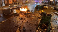 Pengemudi melewati tempat sampah yang terbakar setelah demonstrasi pada hari debat Majelis Nasional dan pemungutan suara pada dua mosi tidak percaya terhadap pemerintah Prancis, yang diajukan oleh kelompok sentris Liot dan partai Nasional Rassemblement sayap kanan. REUTERS/Bart Biesemans