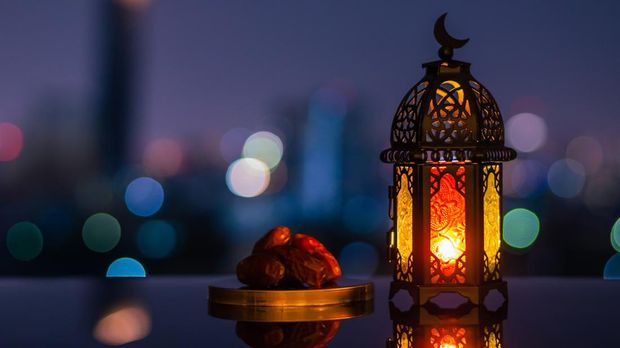 Lantern that have moon symbol on top and small plate of dates fruit with night sky and city bokeh light background for the Muslim feast of the holy month of Ramadan Kareem.