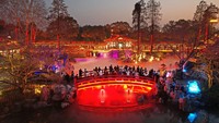 Pengunjung ramai-ramai menikmati tur malam di taman yang diterangi lampu warna-warni. VCG/Getty Images.