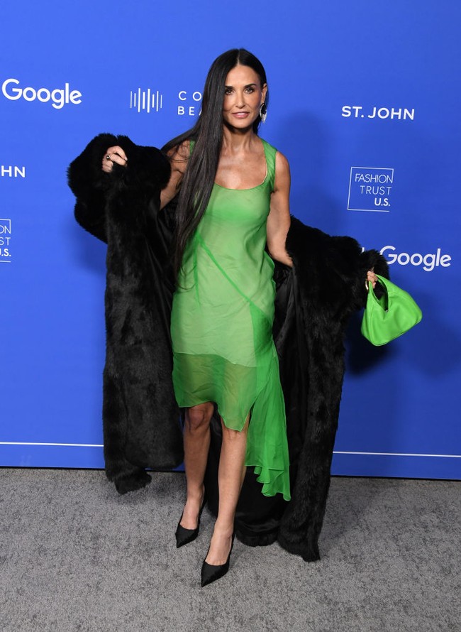Demi Moore sendiri mengenakan dress hijau neon yang merupakan koleksi Givenchy Fall/Winter 2023. Dia memadukannya dengan coat bulu hitam yang matching dengan sepatunya. Foto: Getty Images