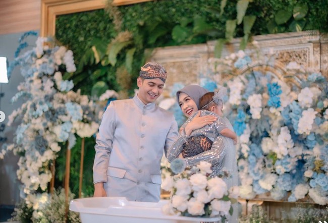 Teuku Ryan dan Ria Ricis terlihat kompak mengenakan busana adat Jawa berwarna biru keabuan, begitu pula dengan baby Moana. Ricis mengenakan kebaya yang dipadukan dengan kerudung berwarna senada, sementara Ryan tampil gagah dengan beskap di kepalanya. Foto: Instagram/@windrafotografi