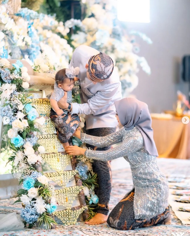 Tedak sinten sinten sendiri merupakan prosesi adat Jawa yang biasanya digelar saat anak pertama kali belajar menginjakkan kaki ke tanah. Terlihat Ricis dan Ryan yang kompak melewati satu demi satu prosesi tedak sinten bersama sang anak. Foto: Instagram/@windrafotografi